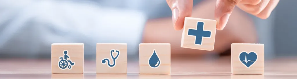 A hand placing a row of blocks with medical symbols on them